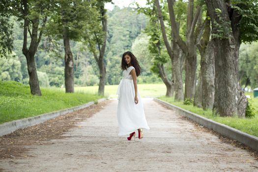 Beautiful young woman walking on the summer park