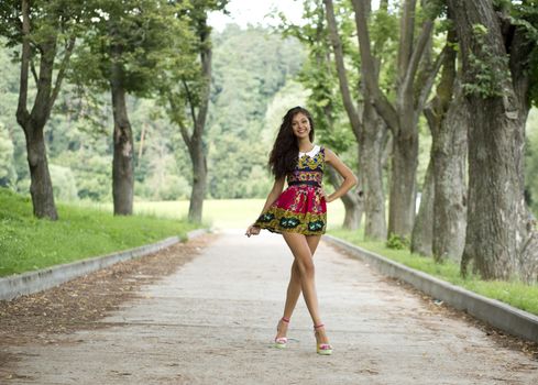 Beautiful young woman walking on the summer park