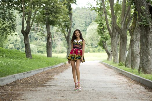 Beautiful young woman walking on the summer park