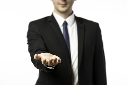 Businessman in a suit holds out his hand with the palm facing upwards isolated on white background