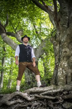 Traditional Bavarian man is standing in a forest in summer