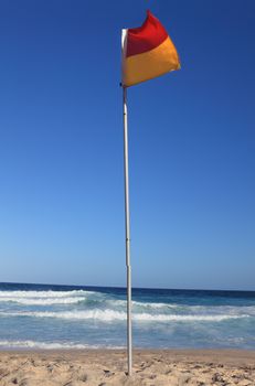 Red and yellow beach flag flapping in the breeze.