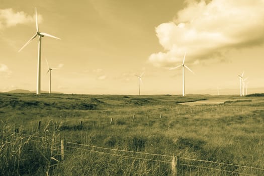 long grass and bogland with wind turbines in the background in Ireland sepia