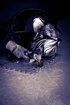 a mechanic welding the exhaust of a motorbike in a garage in selenium tone