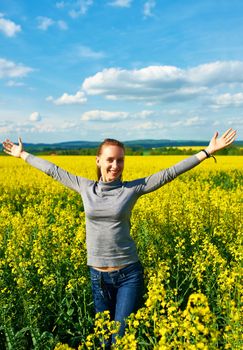 Girl with outstretched arms at colza field