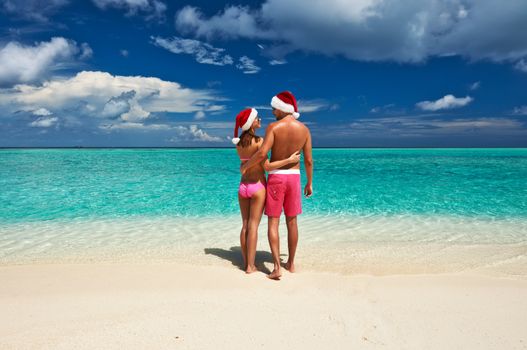 Couple in santa's hat on a tropical beach at Maldives