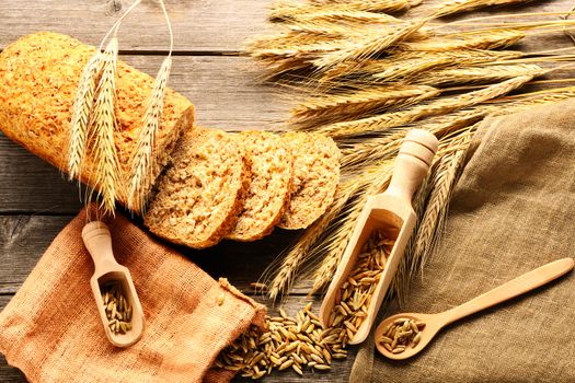 Rye spikelets and bread on wooden background