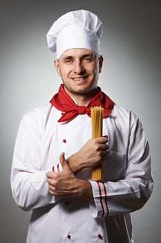 Male chef holding pasta against grey background