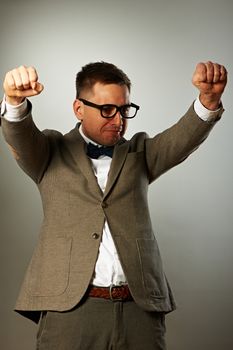 Superhero nerd in eyeglasses and bow tie against grey background