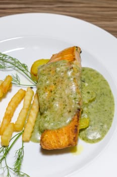 top view roasted salmon served with green sauce and french fries 