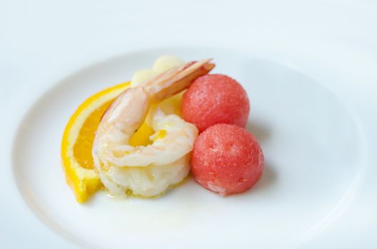  boiled shrimp and mixed fruits ( orange and watermelon ) on plate