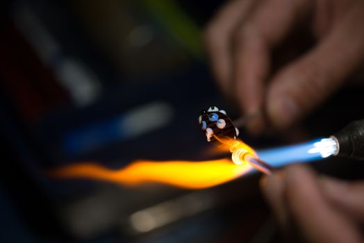 master glassblower shapes the glass warmed by the burner flame
