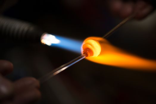 master glassblower shapes the glass warmed by the burner flame