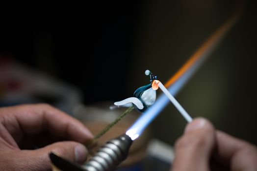 master glassblower shapes the glass warmed by the burner flame