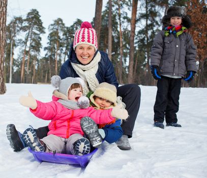 Four kids with mother is sledging in winter-landscape