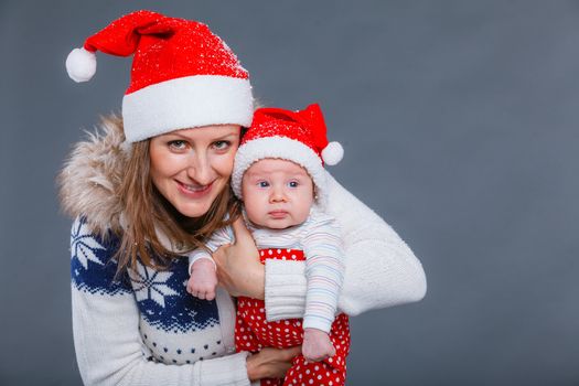 Christmas theme - Portrait of happy mother with babyboy in Santa's hat in studio