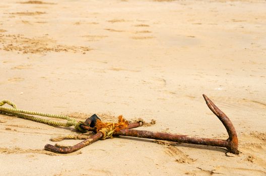 Old rusted anchor buried in sand