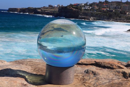 BONDI BEACH, AUSTRALIA - OCTOBER 30, 2013: Sculpture By The Sea, Bondi 2013. Annual event that showcases artists from around the world  Sculpture titled 'Horizon' by Lucy Humphrey (NSW).  Medium acrylic sphere, water, steel, timber and masonry base
