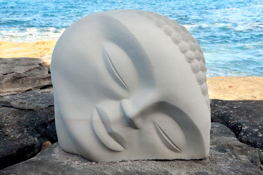 BONDI BEACH, AUSTRALIA - OCTOBER 30, 2013: Sculpture By The Sea, Bondi 2013. Annual event that showcases artists from around the world  Sculpture titled 'Moon Buddha' by Vince Vozzo (NSW).  Medium sandstone
