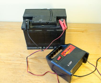 auto battery charger clamps connected to car accumulator at home.