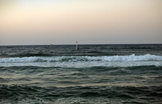 windsurfer silhouette against a sparking blue sea .