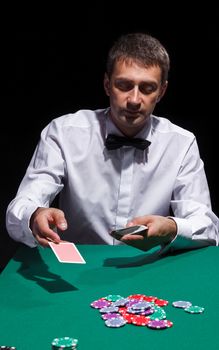 Gentleman in white shirt, playing cards, on black background