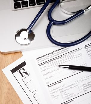 Prescription form with pen stethoscope and laptop computer