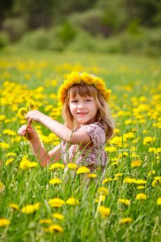Portrait of cute little girl with dandelion wreath enjoying a summer day outdoors