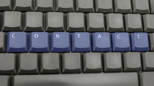 Word contact spelled with blue keys on computer keyboard.