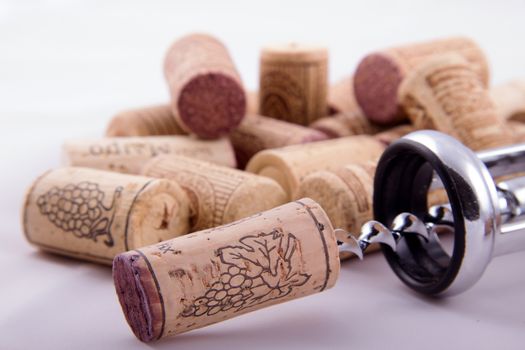Bunch of corks with different designs and corkscrew in a white background