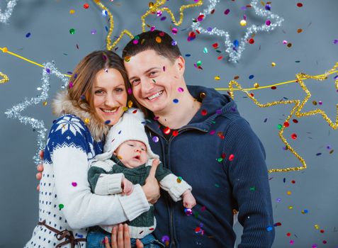 Christmas theme - Portrait of happy family with baby in winter clothing in studio