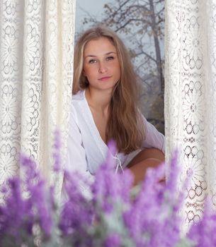 young beautiful woman enjoying her morning near big window in hotel / room