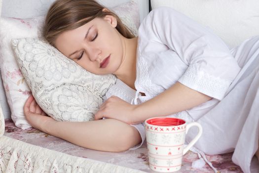 beautiful blond woman awaking with cup of coffee at bedroom