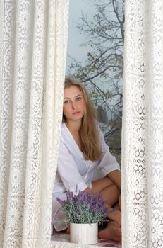 young beautiful woman enjoying her morning near big window in hotel / room