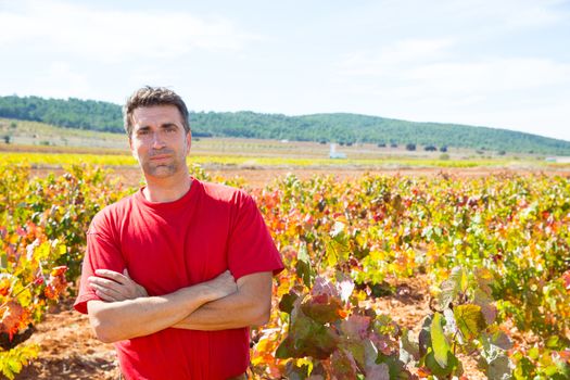 Harvester winemaker farmer proud of his vineyard in autumn golden red leaves at Mediterranean