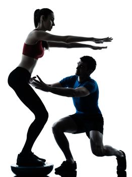 personal trainer man coach and woman exercising squats on bosu silhouette  studio isolated on white background