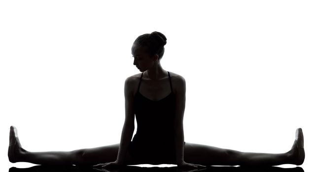 one caucasian young woman ballerina ballet dancer stretching warming up in silhouette studio on white background