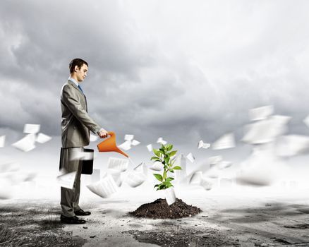 Image of businessman watering sprout with can