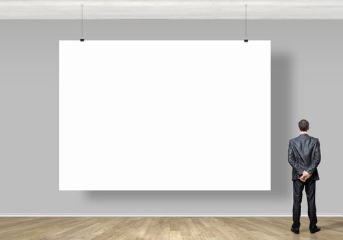 Image of businessman standing with back and looking at white banner