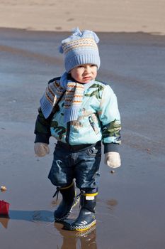 Little boy goes on a pool in rubber boots