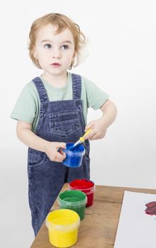 little girl with brush in paint tub. studio shot on light grey background