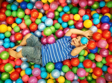 Happy child playing at colorful plastic balls playground high view