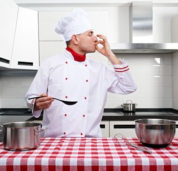 Male chef at kitchen tasting the dish