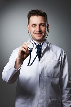 Medical doctor with stethoscope portrait against grey background 