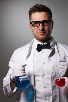 Scientist with chemical flasks against grey background