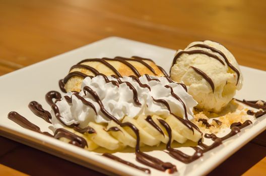 close up crepes with banana , chocolate sauce  served with whipping cream and vanilla ice cream