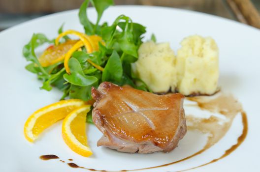 close up  duck breast  served with mashed potatoes , slice of orange and  fresh salad 
