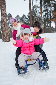 Cute three kids on sleds in snow forest. Focus on the boy