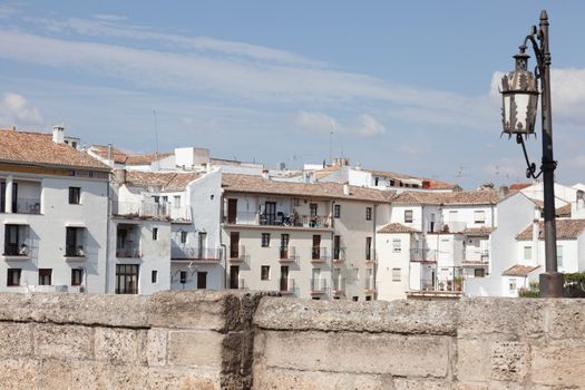 Parapet of the stone bridge, lamp and white houses in Ronda, Spain