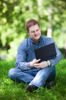 Successful smiling businessman working with laptop in the city park.